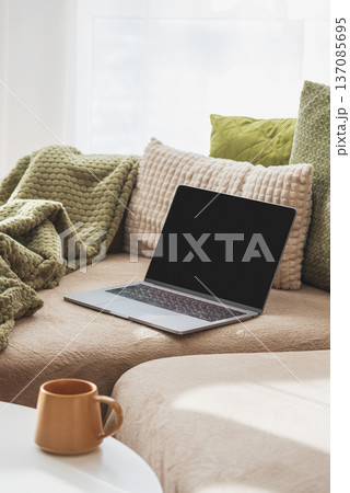 Laptop on Sofa and Coffee Mug on Table. Cozy Spring Home Workspace 137085695
