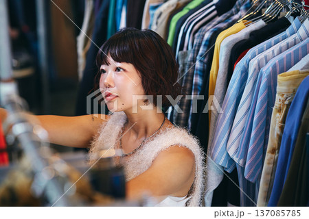 古着店舗のラックを整える若い女性スタッフ 古着店舗のラックを整える若い女性スタッフ 137085785