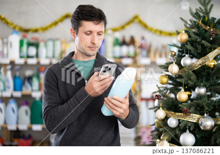 Man client choose and scanning QR code on package shampoo or shower gel Man client choose and scanning QR code on package shampoo or shower gel 137086221