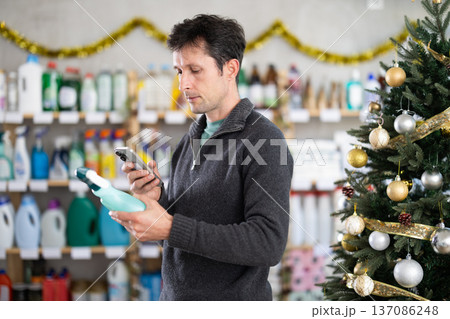 Male client choose and scanning QR code on package glass cleaner spray 137086248