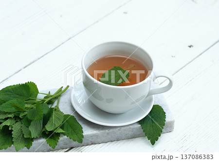 A cup of fresh tea from Melissa officinalis, commonly known as lemon balm or melissa on a marble. 137086383