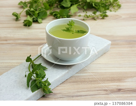 A cup of fresh tea from Chickweed, lat. Stellaria media on white marble. 137086384