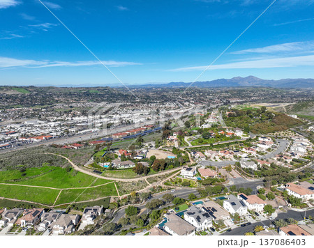 Aerial view over San Juan Capistrano, California, featuring the historic mission, library, sports courts, and an Amtrak train pulling into the downtown station. Aerial view over San Juan Capistrano, California, featuring the historic mission, library, sports courts, and an Amtrak train pulling into the downtown station. 137086403