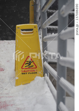 Caution sign shows wet floor during snow weather 137086890