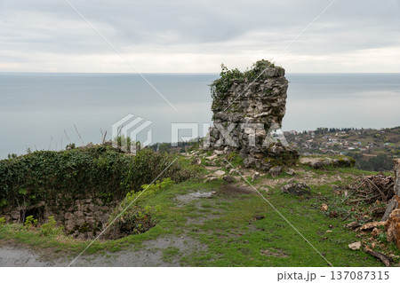 Anakopia fortress stone tower ruins overlooking Black Sea coastline and New Athos landscape under overcast sky in Abkhazia. Heritage tourism marketing, travel branding, history education 137087315