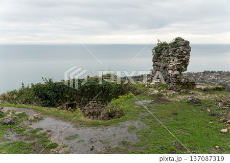 Anakopia fortress stone tower ruins overlooking Black Sea coastline and New Athos landscape under overcast sky in Abkhazia. Heritage tourism marketing, travel branding, history education Anakopia fortress stone tower ruins overlooking Black Sea coastline and New Athos landscape under overcast sky in Abkhazia. Heritage tourism marketing, travel branding, history education 137087319
