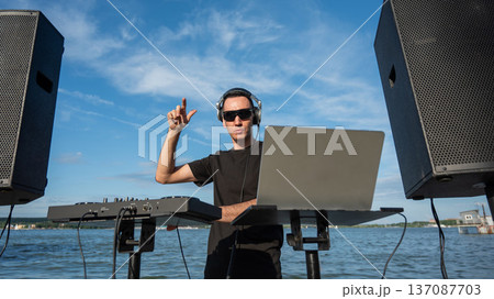 Caucasian man works as a DJ on the beach. Caucasian man works as a DJ on the beach. 137087703