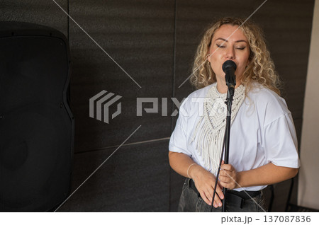 Caucasian woman singing into microphone in music studio. Caucasian woman singing into microphone in music studio. 137087836