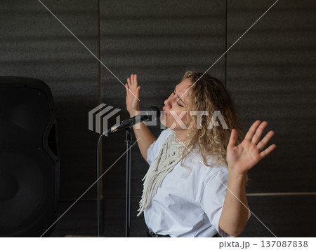 Caucasian woman singing into microphone in music studio.  137087838