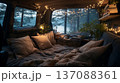 Cozy interior of a van with soft pillows and blankets, illuminated by string lights, surrounded by trees and a lake view through the windows at dusk 137088361