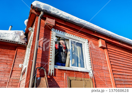 After installing outdoor dome surveillance camera on facade of farmhouse rural resident connects power supply to it After installing outdoor dome surveillance camera on facade of farmhouse rural resident connects power supply to it 137088628