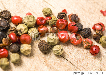 A bunch of different colored peppers are scattered on a wooden surface. The peppers are of various sizes and colors, including red, green, and yellow. Concept of abundance and variety A bunch of different colored peppers are scattered on a wooden surface. The peppers are of various sizes and colors, including red, green, and yellow. Concept of abundance and variety 137089131