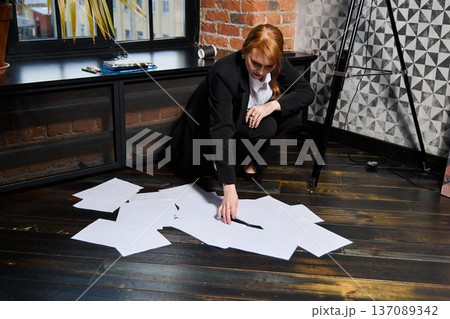 Woman with fiery hair arranging scattered designs urgently Woman with fiery hair arranging scattered designs urgently 137089342