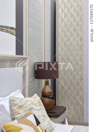 Cozy bedside scene with wooden lamp and textured headboard Cozy bedside scene with wooden lamp and textured headboard 137089370