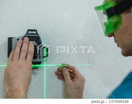 A man measures distance with a laser level. A man measures distance with a laser level. 137089586