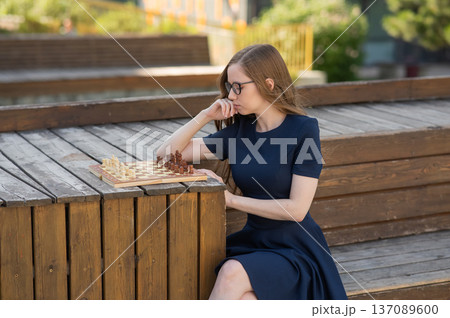 Caucasian woman playing chess outdoors. Caucasian woman playing chess outdoors. 137089600