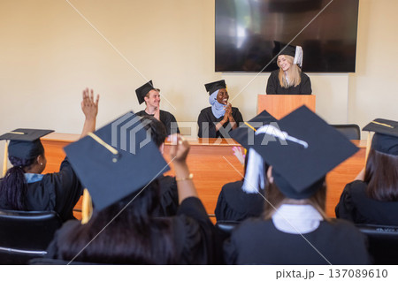 A young woman stands at the lectern and delivers a graduation speech to her classmates. A young woman stands at the lectern and delivers a graduation speech to her classmates. 137089610