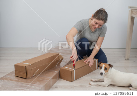 A Caucasian woman unpacks a box of furniture. 137089611
