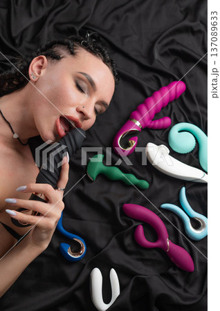 Portrait of Caucasian woman lying on bed among sex toys. Portrait of Caucasian woman lying on bed among sex toys. 137089633