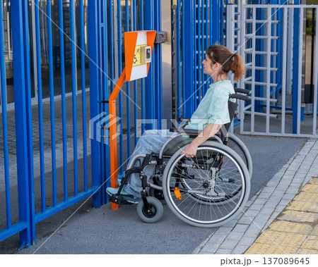 A woman in a wheelchair uses a touch-sensitive Braille help button..  137089645