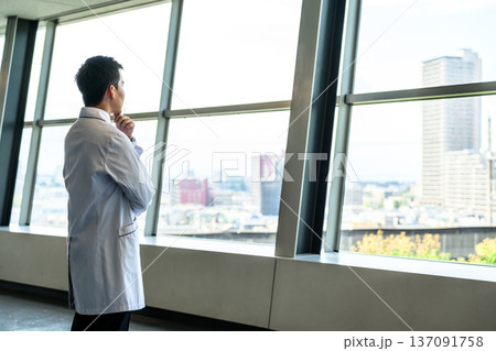 白衣の男性が窓外を見る 137091758