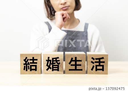 「結婚生活」と書かれたブロックとエプロン姿で悩む女性 137092475