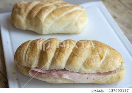 ham sandwich roll with crusty bread on white cutting board 137093157