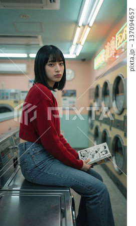 洗濯機の上に座り漫画を読む赤いセーターの日本人女性 137094657