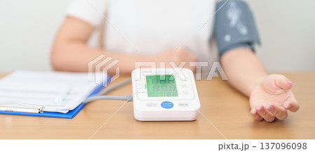 woman checking Blood pressure by Blood pressure monitor with Cuff. Systolic, SYS, Diastolic, DIA, Pulse, Hypertension, Hypotension, Heart rate, Cardiovascular Disease and May World hypertension day 137096098