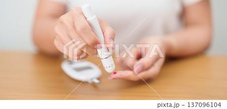 Hand using lancet pen on finger with Blood drop glucose testing or Diabetes checking by digital blood glucose meter. blood sugar level, Diabetes Day, Glycemia, Hypoglycemia, Hyperglycemia and insulin Hand using lancet pen on finger with Blood drop glucose testing or Diabetes checking by digital blood glucose meter. blood sugar level, Diabetes Day, Glycemia, Hypoglycemia, Hyperglycemia and insulin 137096104