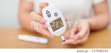 Hand checking Diabetes or Blood glucose self testing by digital blood glucose meter with lancet pen. high blood sugar level, World Diabetes Day, Glycemia, Hypoglycemia, Hyperglycemia and insulin 137096105