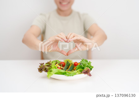 happy smiling woman with fresh organic vegetables plate and heart shape gesture. healthy nutrition, weight loss, clean eating, Healthy food eating, Vegan, Wellness, Green dieting and Healthy lifestyle 137096130