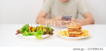 happy woman with Healthy and Unhealthy Food Choice. Comparison of Calories and Nutrition of vegetables Salad plate and Hamburger. diet planning, weight loss management, junk food and habit lifestyle 137096141