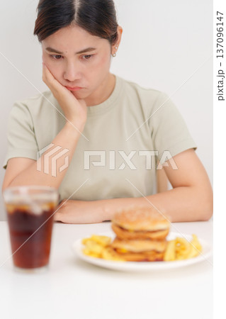Unhappy woman disgust gesture and Bored to eat Juicy beef burger, potato chips and carbonated Soft drinks. Unhealthy, High calorie, Fast food craving, Obesity, diet, weight loss and junk food Unhappy woman disgust gesture and Bored to eat Juicy beef burger, potato chips and carbonated Soft drinks. Unhealthy, High calorie, Fast food craving, Obesity, diet, weight loss and junk food 137096147