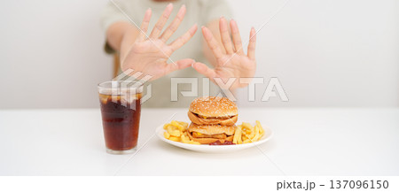 Unhappy woman showing Rejecting and refusing with Juicy beef burger, potato chips and carbonated Soft drinks. Unhealthy, High calorie, Fast food craving, Obesity, diet, weight loss and junk food Unhappy woman showing Rejecting and refusing with Juicy beef burger, potato chips and carbonated Soft drinks. Unhealthy, High calorie, Fast food craving, Obesity, diet, weight loss and junk food 137096150