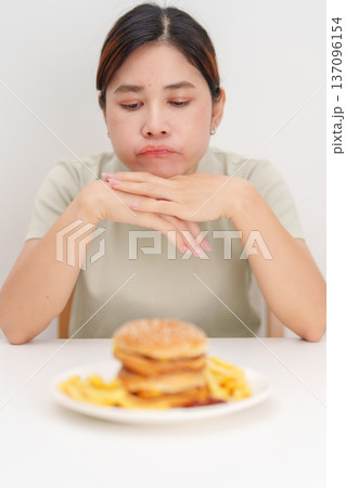 Unhappy woman disgust gesture and Bored to eat Juicy beef burger and potato chips. Unhealthy, High calorie, Fast food craving, Obesity, diet, weight loss and junk food 137096154