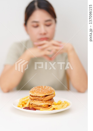 Unhappy woman disgust gesture and Bored to eat Juicy beef burger and potato chips. Unhealthy, High calorie, Fast food craving, Obesity, diet, weight loss and junk food 137096155