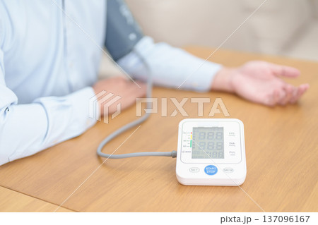 Man checking Blood pressure by Blood pressure monitor with Cuff. Systolic, SYS, Diastolic, DIA, Pulse, Hypertension, Hypotension, Heart rate, Cardiovascular Disease and May World hypertension day 137096167