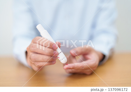 Hand using lancet pen on finger with Blood drop glucose testing or Diabetes checking by digital blood glucose meter. blood sugar level, Diabetes Day, Glycemia, Hypoglycemia, Hyperglycemia and insulin Hand using lancet pen on finger with Blood drop glucose testing or Diabetes checking by digital blood glucose meter. blood sugar level, Diabetes Day, Glycemia, Hypoglycemia, Hyperglycemia and insulin 137096172