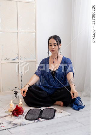 Sadhu board. Woman practice yoga. Sitting in lotus position mudra hands before sharp nails on mat in front of burning fire candles spiritual growth mental health. 137096226