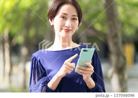 並木道でスマートフォンを操作している若い女性 並木道でスマートフォンを操作している若い女性 137098096