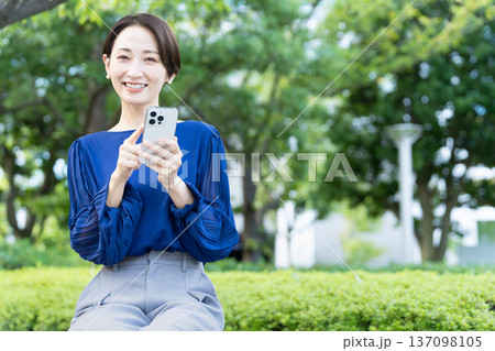 屋外でスマートフォンを操作している若い女性 137098105