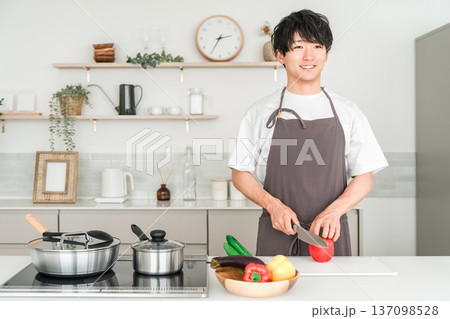 キッチンで料理をするエプロン姿の若いアジア人男性 キッチンで料理をするエプロン姿の若いアジア人男性 137098528