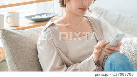 リビングのソファに座りスマホを見るアジア人女性 137098703