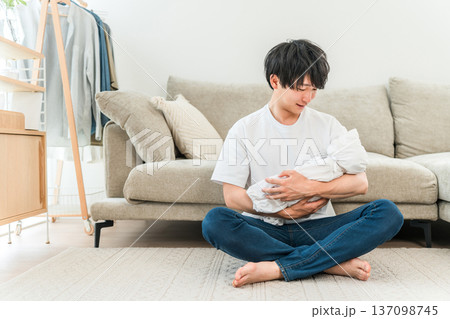 リビングで赤ちゃんを抱っこする若いアジア人男性 リビングで赤ちゃんを抱っこする若いアジア人男性 137098745