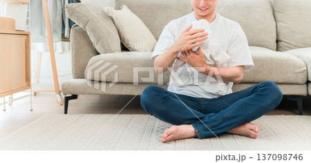 リビングで赤ちゃんを抱っこする若いアジア人男性 リビングで赤ちゃんを抱っこする若いアジア人男性 137098746