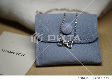 Silver Bow Necklace on Blue Pouch Jewelry Display 137099339