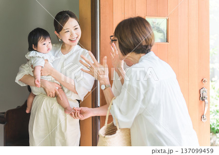 田舎から遊びに来た,旅行に来た両親を玄関先で迎える娘と孫 137099459