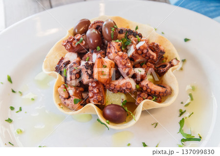 Tasty grilled octopus with potato and olive on a table in restaurant. Top view 137099830