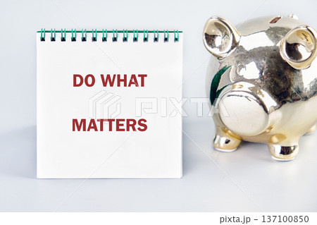 Golden piggy bank by DO WHAT MATTERS notebook on white. Inspires mindful saving and purposeful living Golden piggy bank by DO WHAT MATTERS notebook on white. Inspires mindful saving and purposeful living 137100850